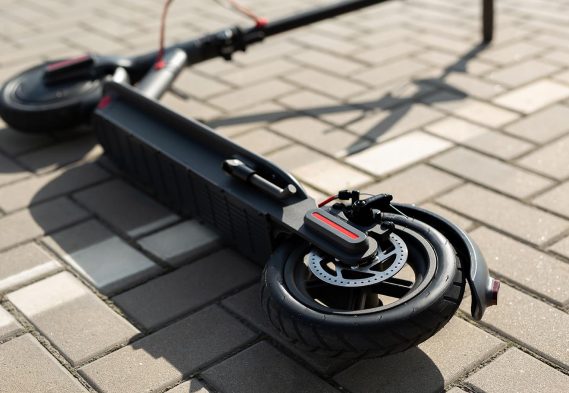 An electric scooter is lying on the sidewalk